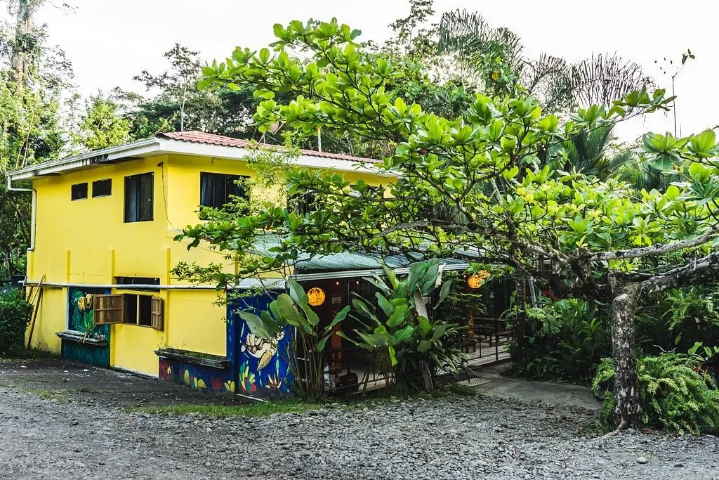 Casa amarilla de la cocina y el comedor rodeada de árboles