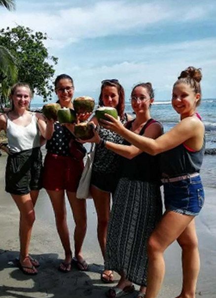 Grupo de estudiantes en la playa con cocos