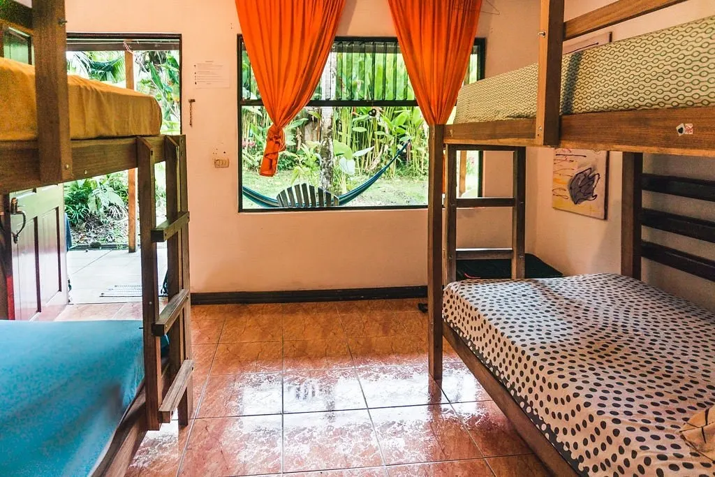Habitación compartida con camarotes de madera y cortinas naranjas