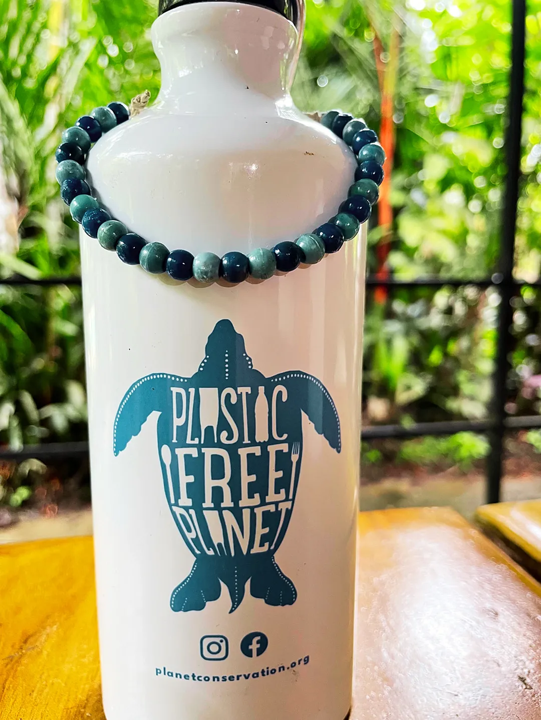 Botella reutilizable con el diseño Plastic Free Planet, sobre una mesa