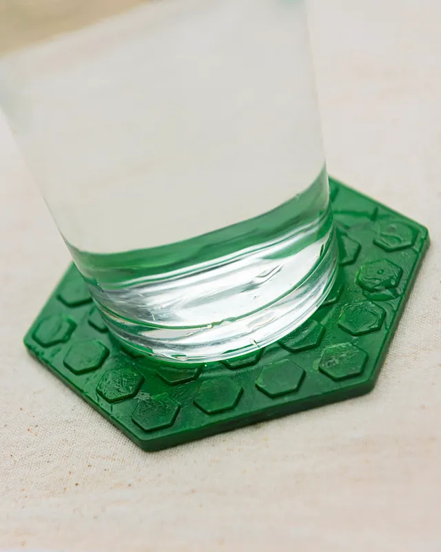 Un vaso de agua sobre un posavasos verde
