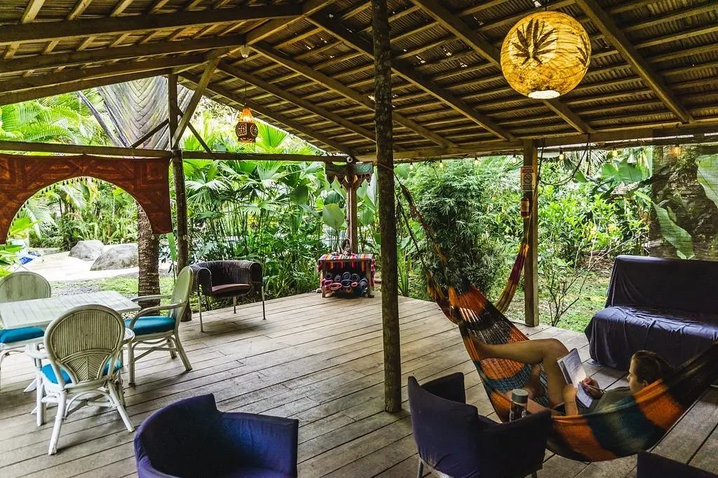 Rancho abierto de madera con hamaca y sillones, usado como espacio de yoga